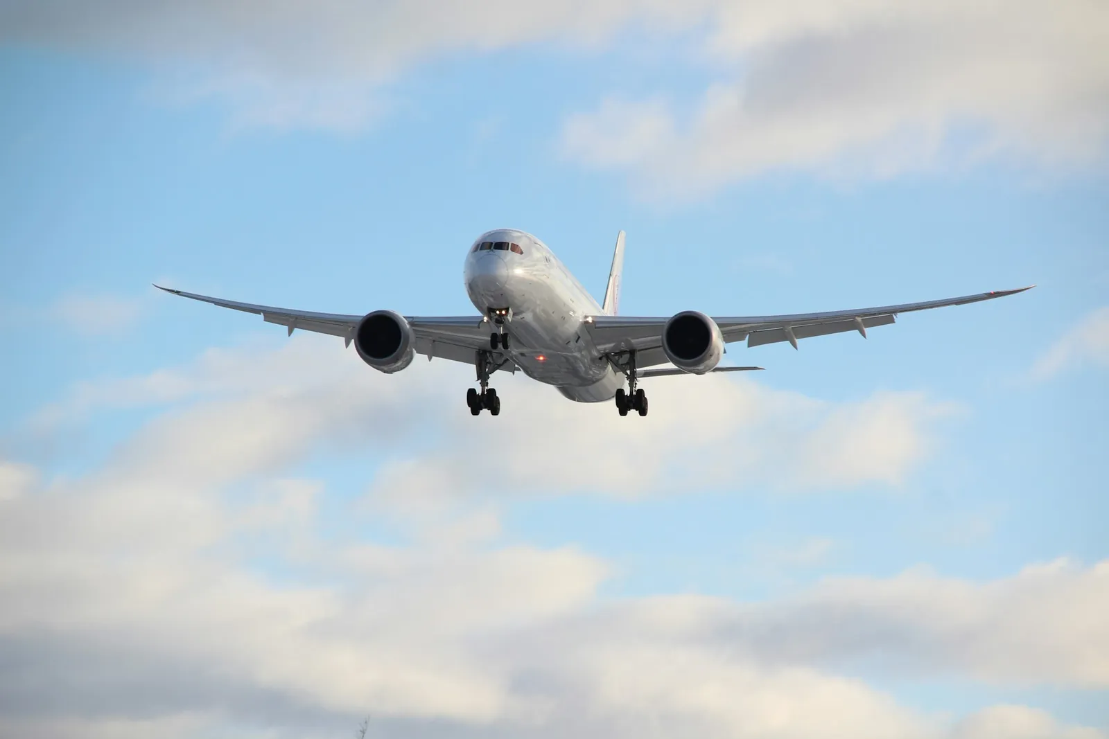 Passenger jet flying through a blue sky with white clouds