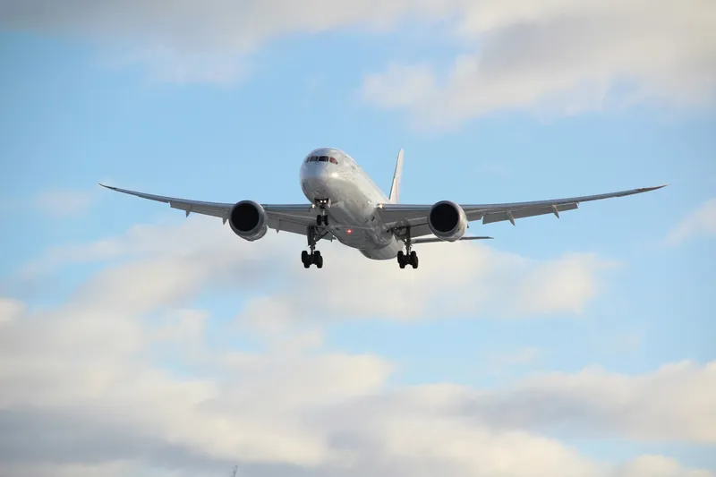 Passenger jet flying through a blue sky with white clouds