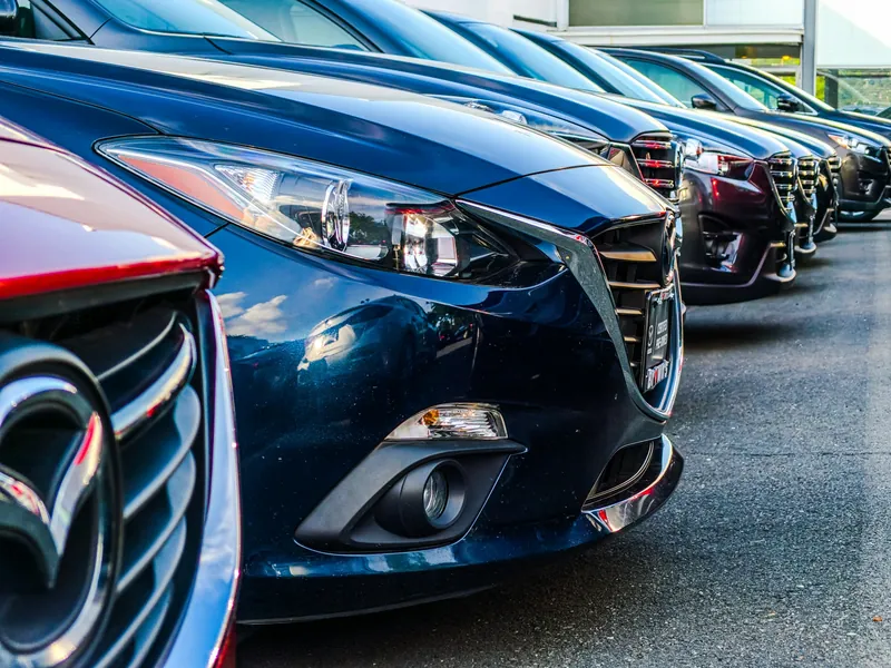Row of new cars parked at a dealership, seen from the front