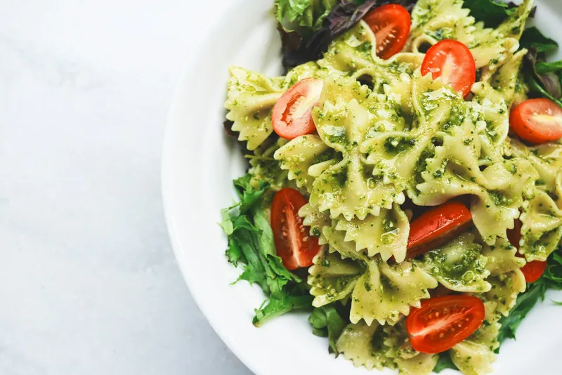 Bowl of farfalle pasta with pesto, cherry tomatoes and salad leaves