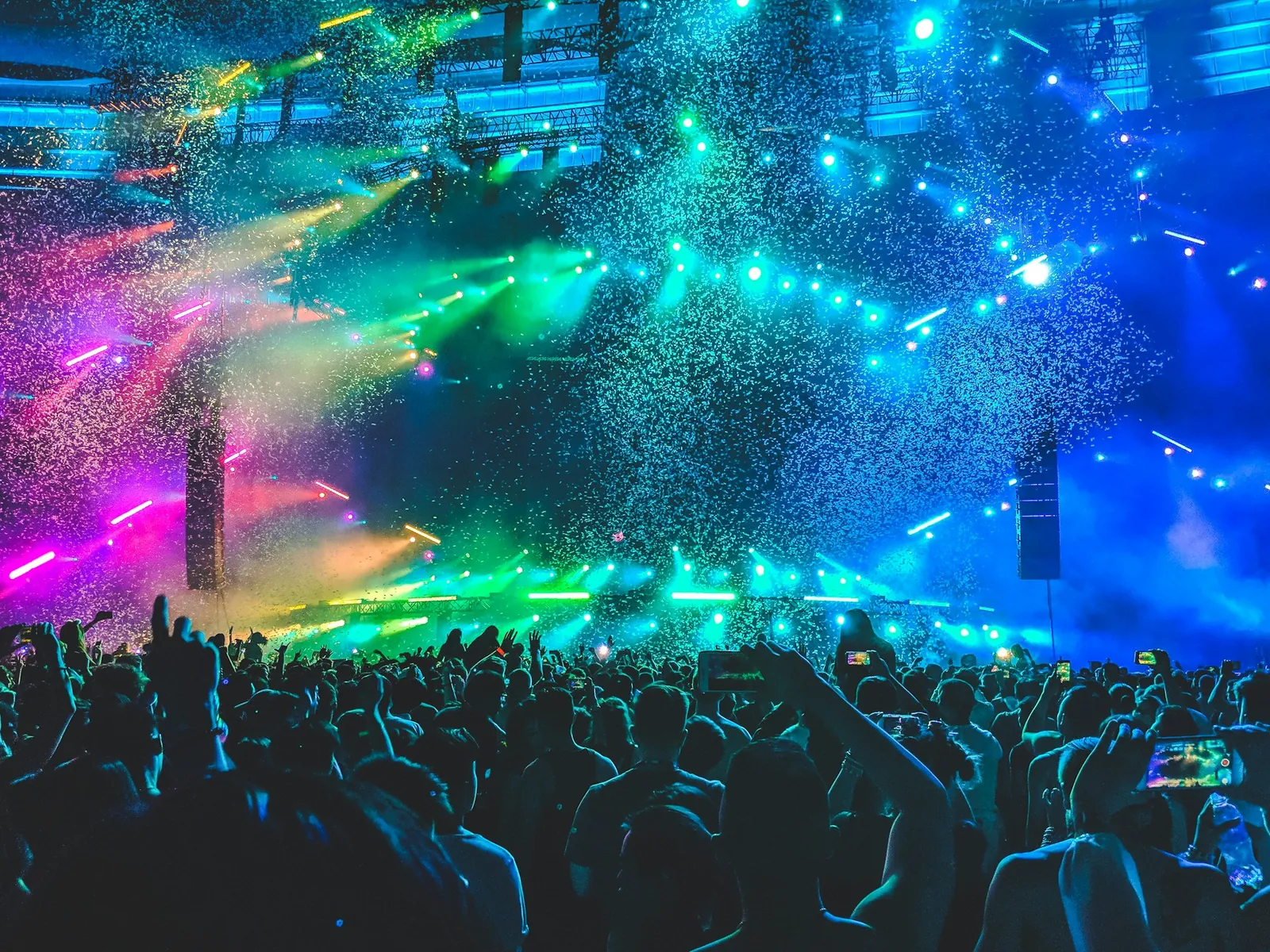 Concert crowd under blue and green stage lights and confetti