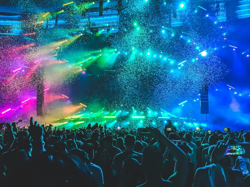 Concert crowd under blue and green stage lights and confetti