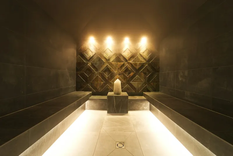 Softly lit spa steam room with stone benches and warm wall lights