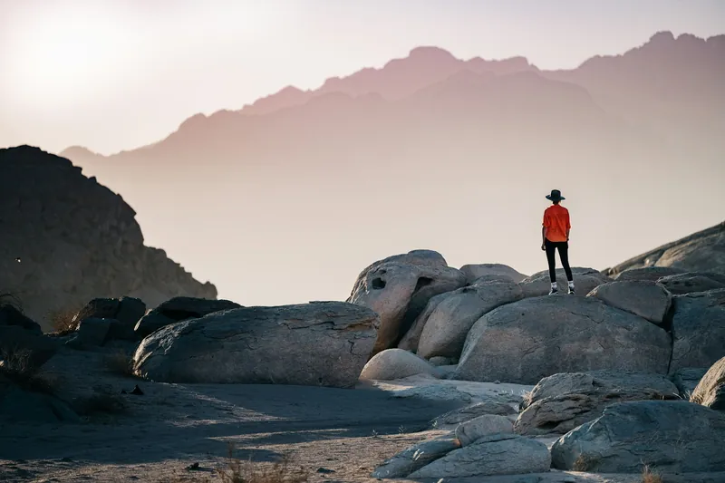 Traveller standing on desert rocks facing misty mountains